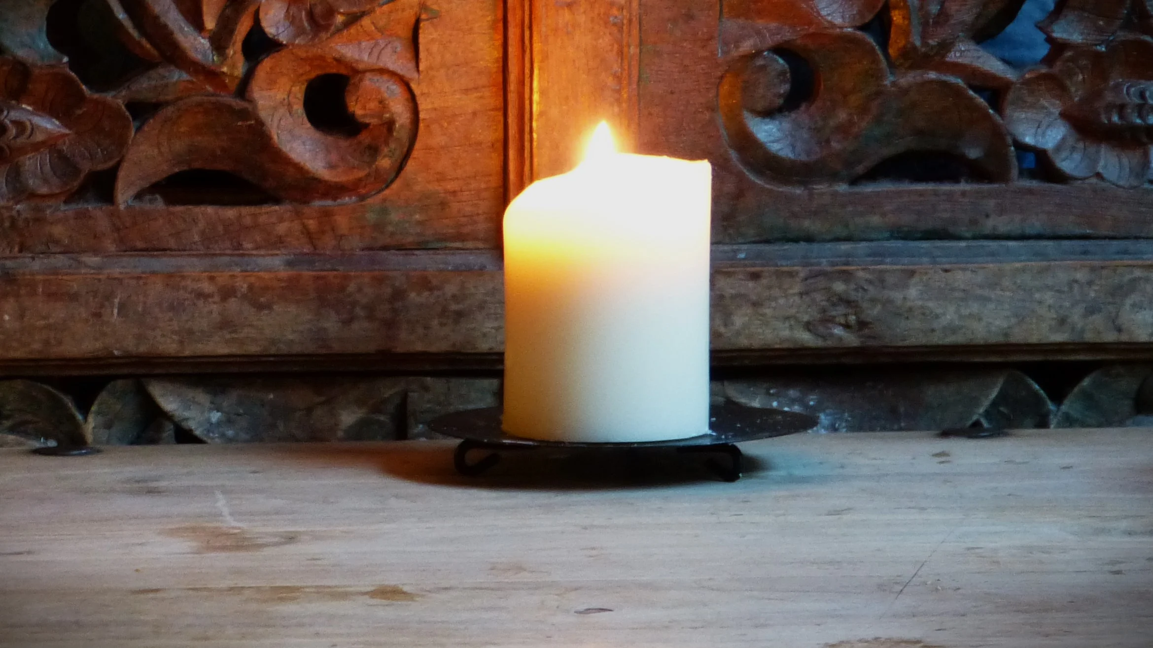 Auf einem Holztisch steht eine Kerze.
